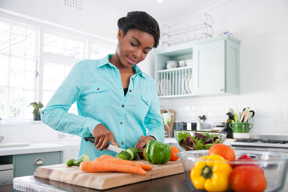 African American woman cutting up vegetables in the kitchen